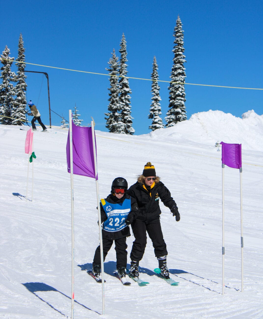 Two people on skis participating in the Winter Special Olympics.