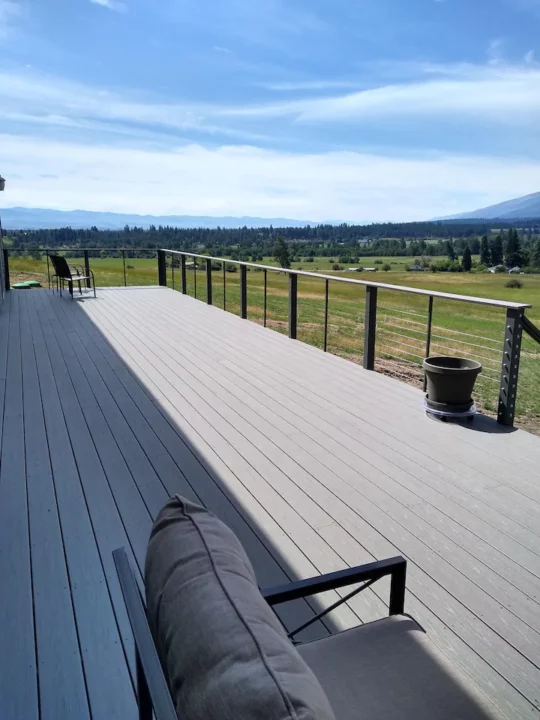 A deck with a stunning view of a field and majestic mountains.
