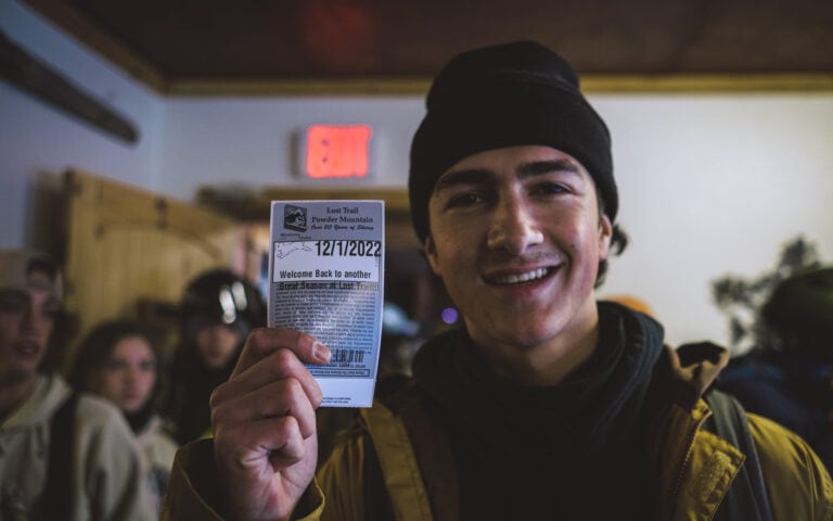 A man holding up a Ski ticket in front of a group of people at Lost Trail Ski Area.
