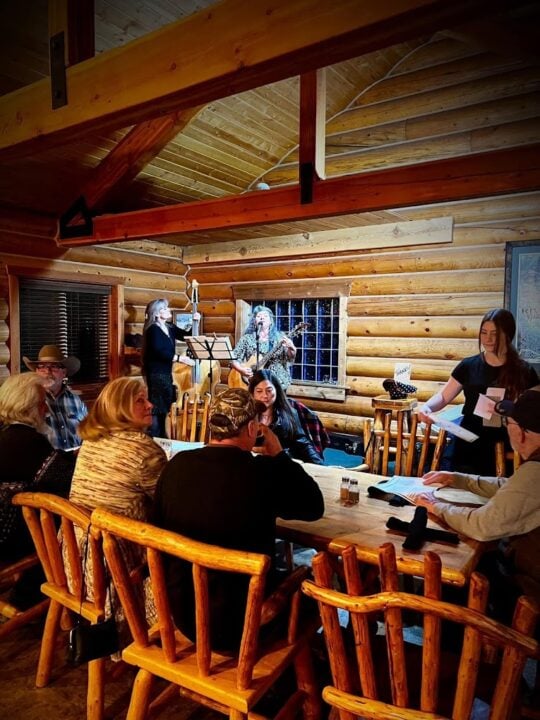 A group of people sitting around a table in a log cabin at Lost Trail Ski Area.