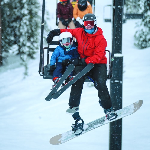 A group of people riding a ski lift in the snow at Lost Trail.