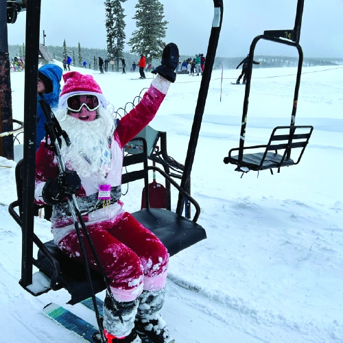 A Santa Claus enjoying a ski lift ride at Lost Trail Ski Area.