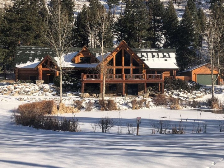A cozy log cabin nestled among snow-covered trees at Lost Trail Ski Area.