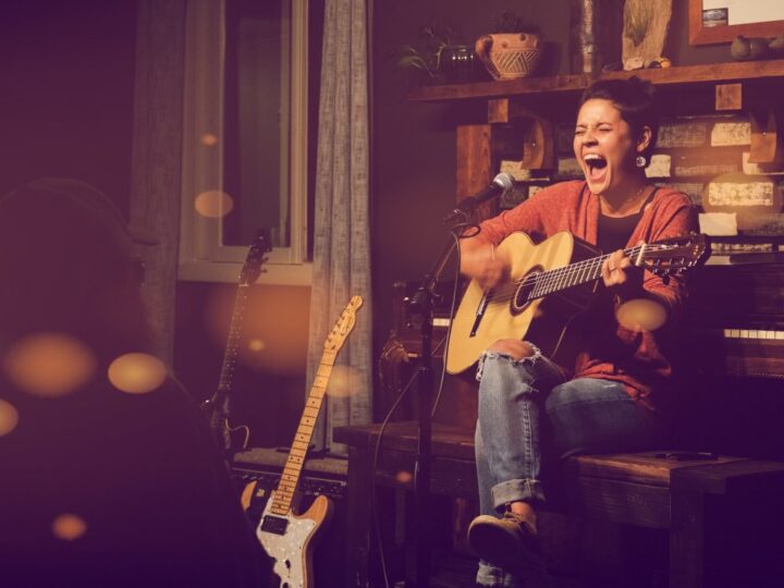 Maria Zepeda passionately performing with an acoustic guitar on a cozy après-ski stage.