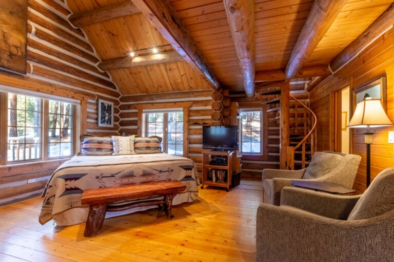 A cozy bedroom in a log cabin equipped with a comfortable bed and a relaxing couch, perfect for unwinding after an exciting day at Lost Trail Ski Area.