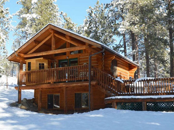 A log cabin in the snow with a deck near Lost Trail Ski Area.