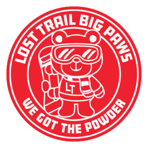 Illustration of a bear in ski gear holding a snowboard. Text around reads: "Lost Trail's Big Paws. We Got the Powder.