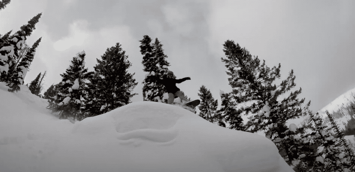 Nat Wilson, a snowboarder, carving his way down a mountain covered in snow.