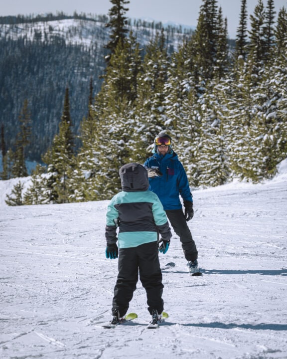 A man and a child skiing on a snowy slope at Lost Trail Ski Area.