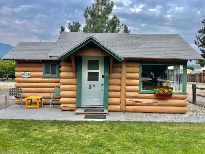 The Lost Trail Ski Area features a quaint log cabin nestled amidst a picturesque grassy area.